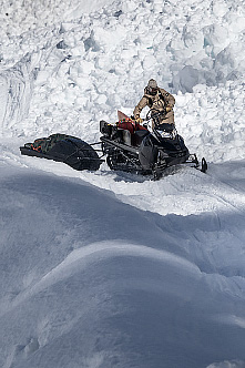 Bryan Fox navigates a snowmobile and trailer-sled along newly forged snowy mountain trail